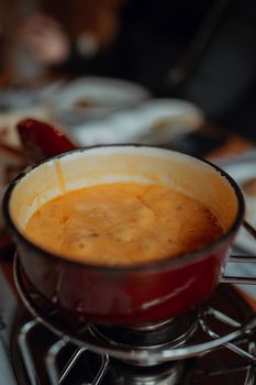Delicious cheese fondue served in rustic red pot, perfect for cozy gatherings and culinary delights.