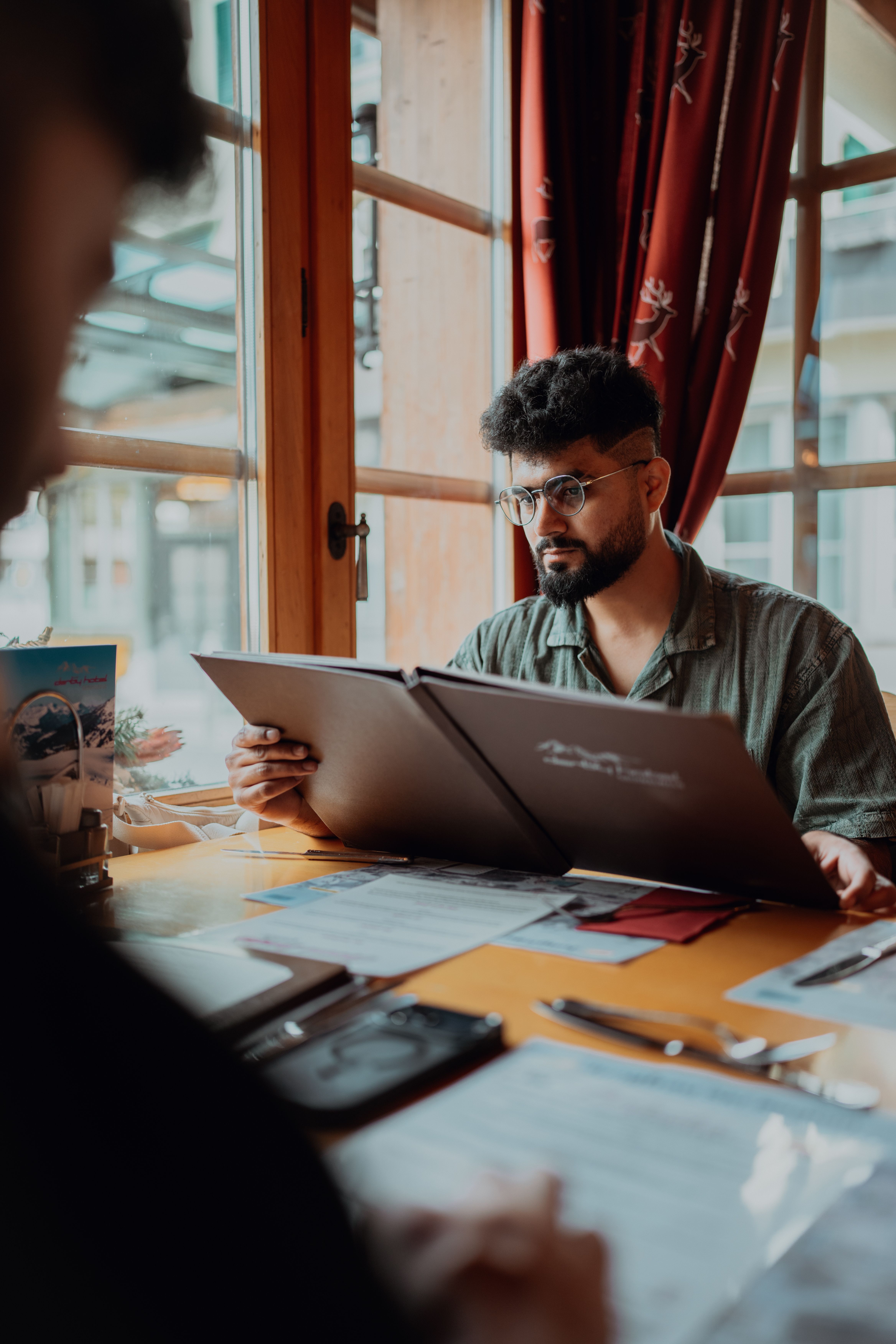 Man Browsing Menu in Cozy Restaurant Setting · Free Stock Photo