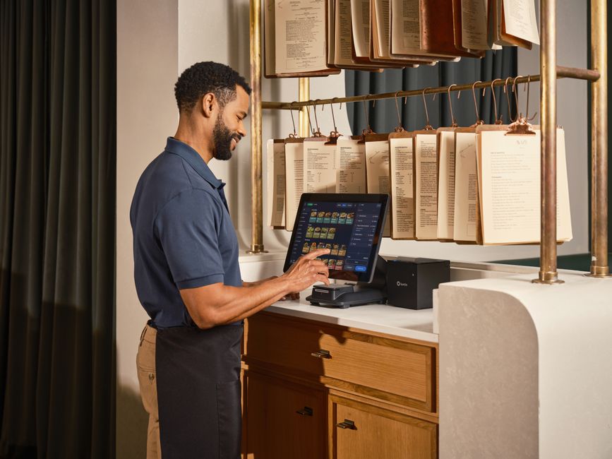 A restaurant server operates a touchscreen POS system, enhancing efficient order management.