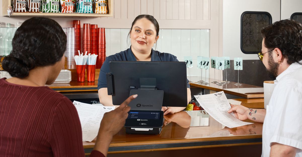 Restaurant staff take orders at a POS system, showcasing modern dining technology.