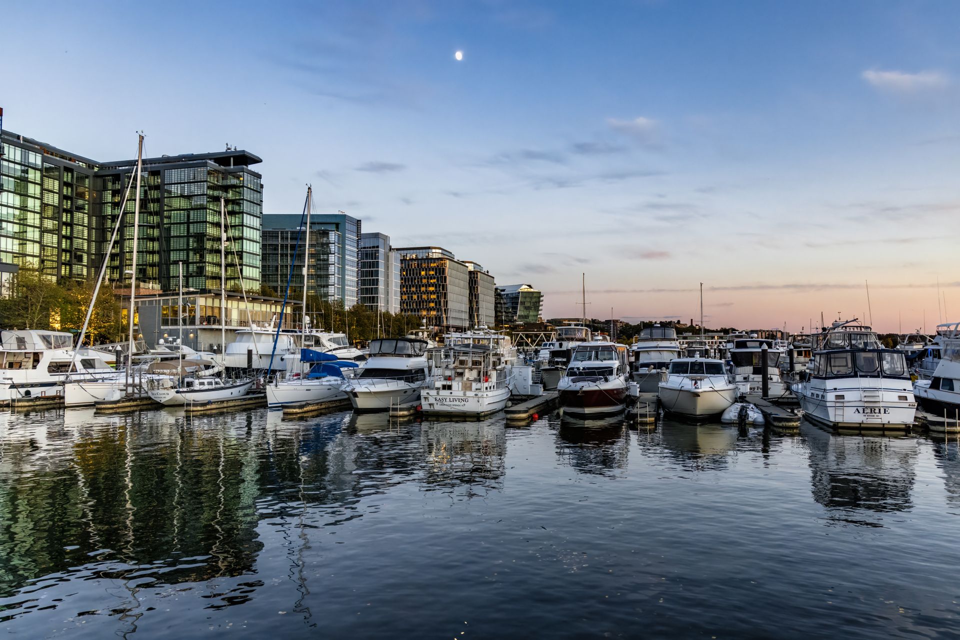 Navy Yard waterfront in Washington DC with modern residential buildings, sailboats, and marina at dusk