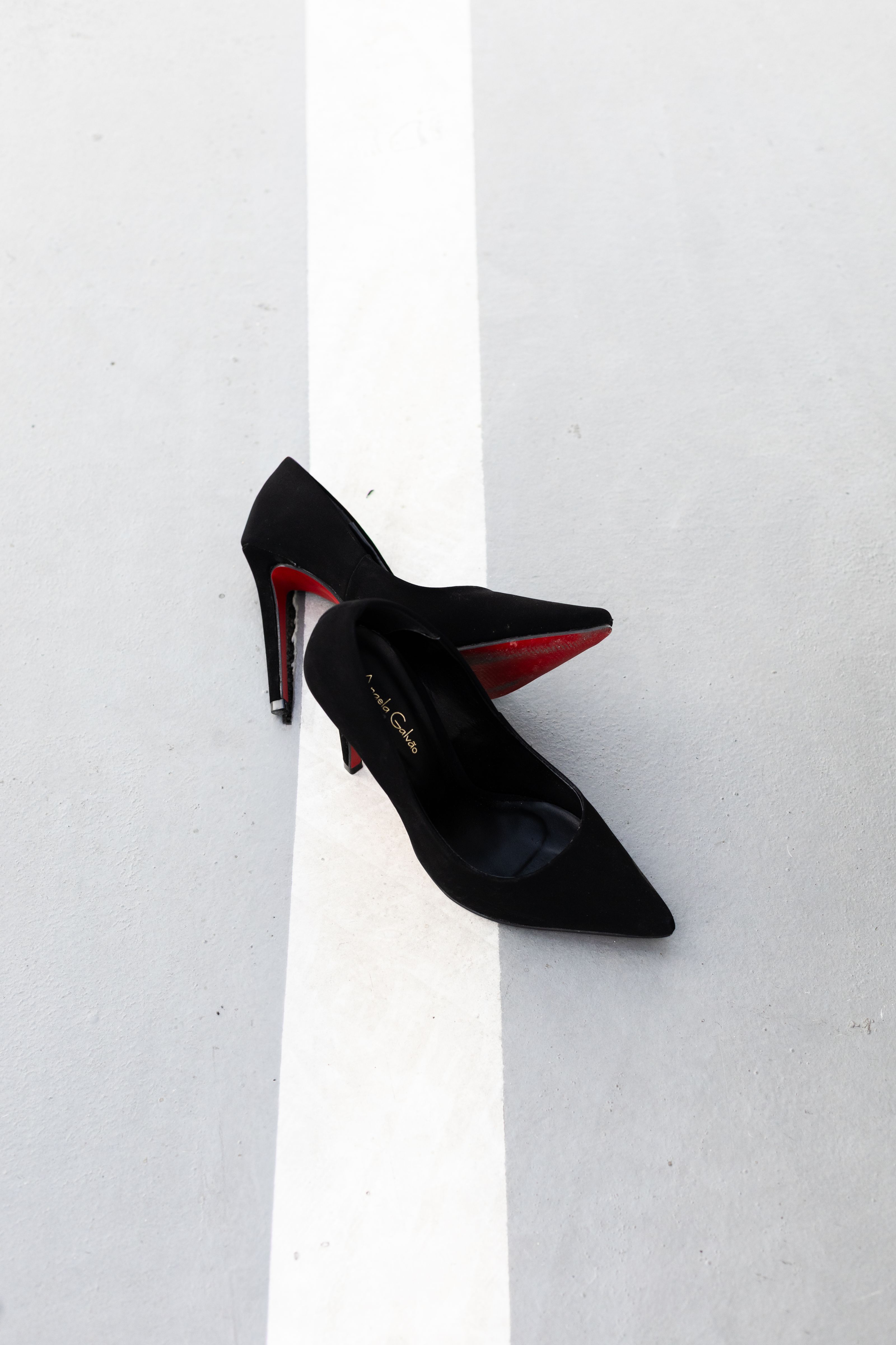 Elegantes sapatos de salto alto pretos com solas vermelhas, dispostos com sofisticação em um estilo urbano despojado, capturam a essência da moda clássica.