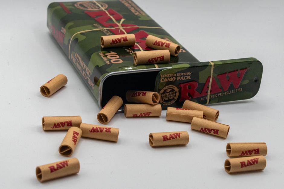 Close-up of a camo pack of RAW brand pre-rolled tips spilling out of the box. Close-up of a camo pack of RAW brand pre-rolled tips spilling out of the box.