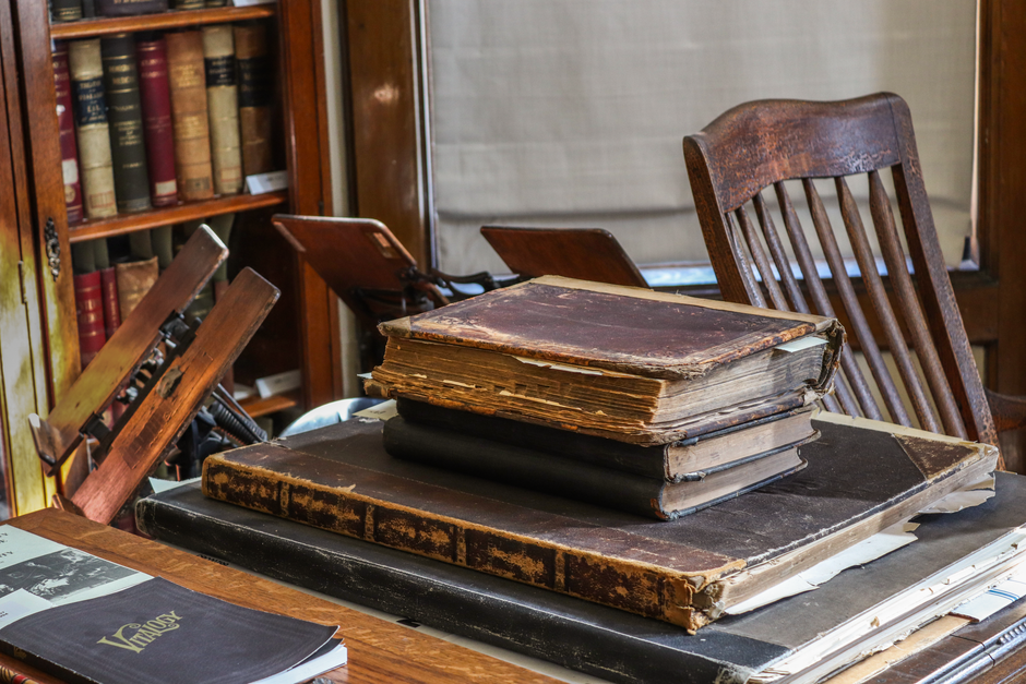 A collection of vintage books and classic wooden furniture in an antique library setting, highlighting history and literature.