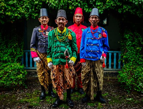 Free Four men in traditional Javanese attire standing solemnly outdoors amidst lush greenery. Stock Photo