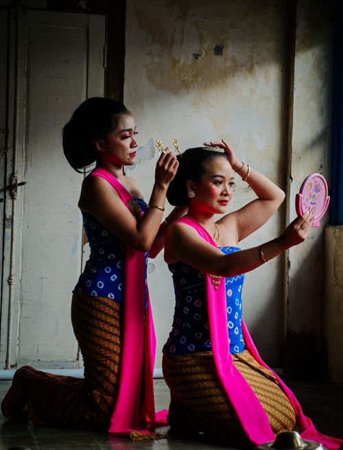 Free Two women in traditional attire prepare backstage, adding ornate headdresses. Stock Photo