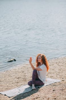 A serene yoga session by the beach with a woman enjoying the peaceful outdoor setting.