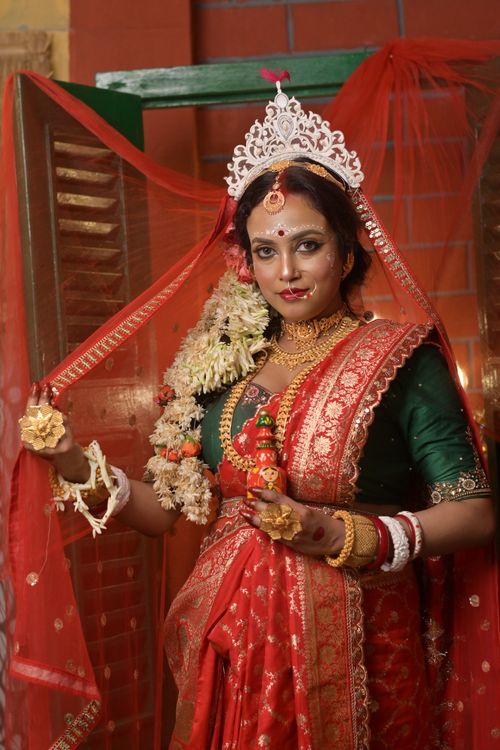 Free Portrait of a Bengali bride in vibrant red saree and gold jewelry, embracing cultural elegance. Stock Photo