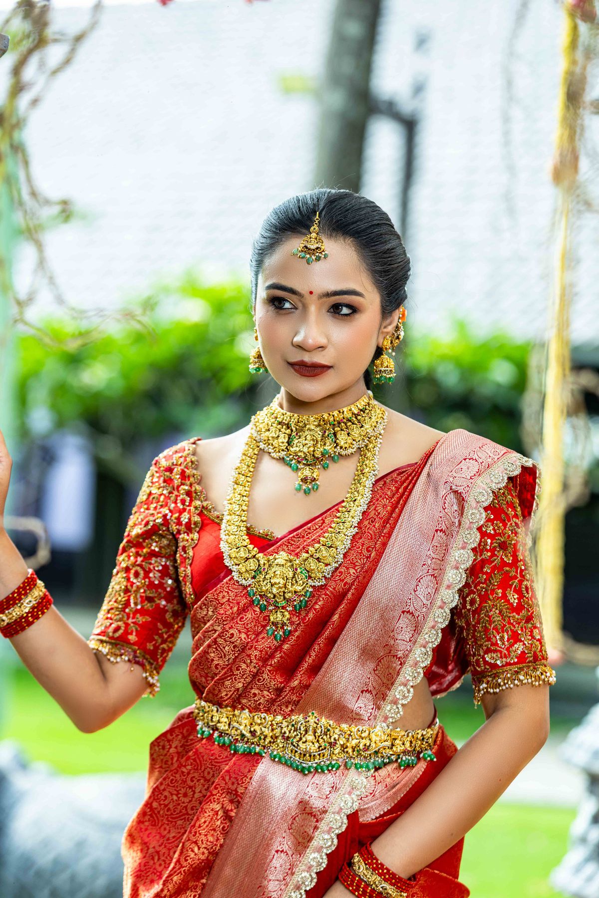 Bride in a red and ivory silk saree with gold jewellery