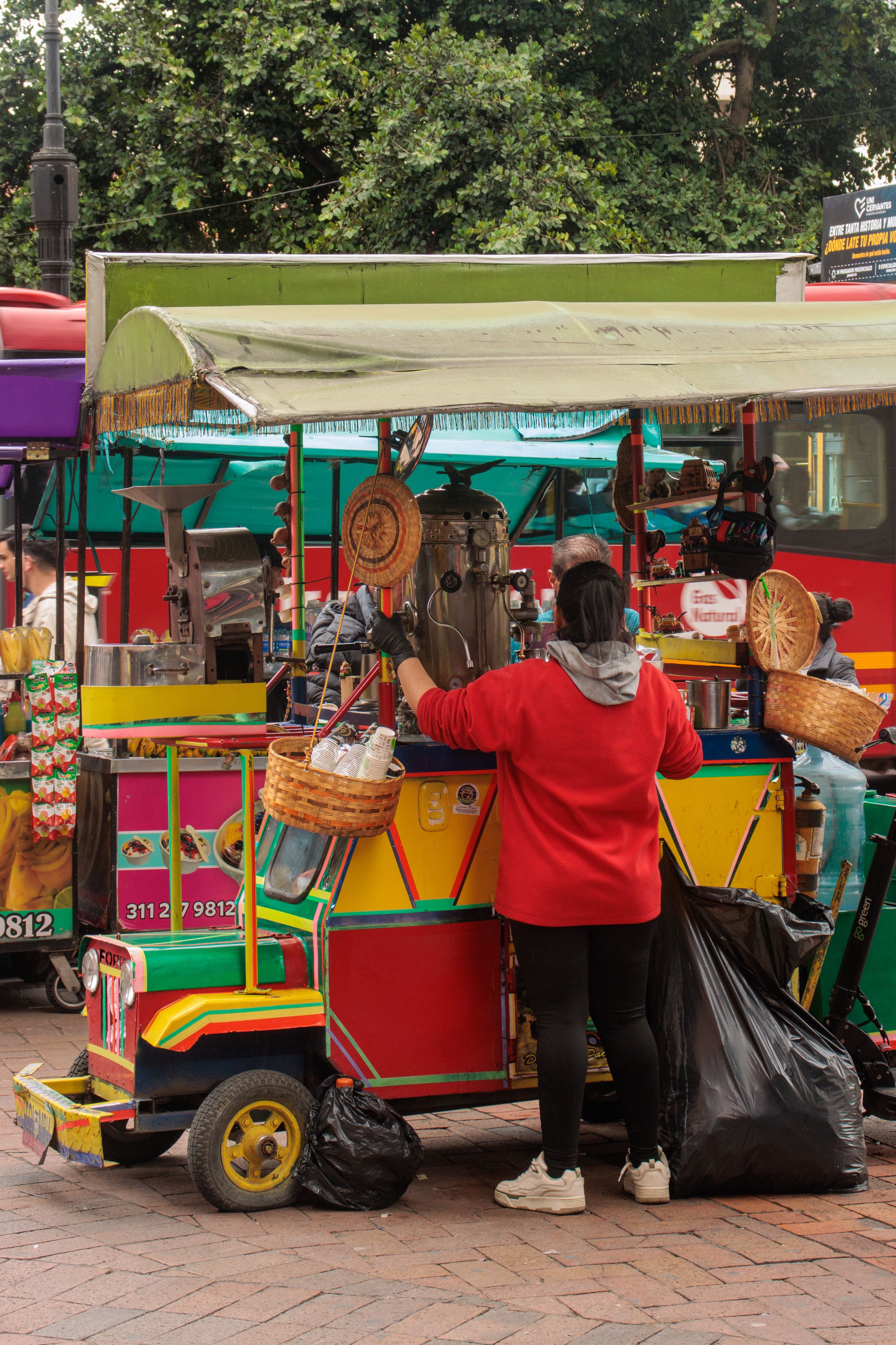 Colorful street food cart in Bogotá serving local Colombian dishes to passersby