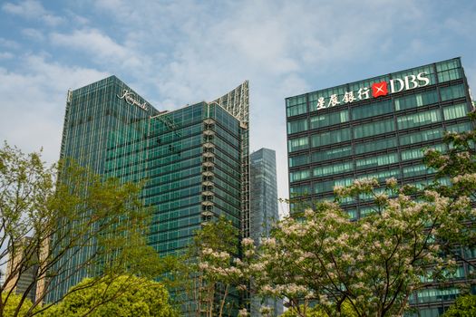 Modern skyscrapers in Shanghai's Pudong District, surrounded by spring blossoms and greenery.