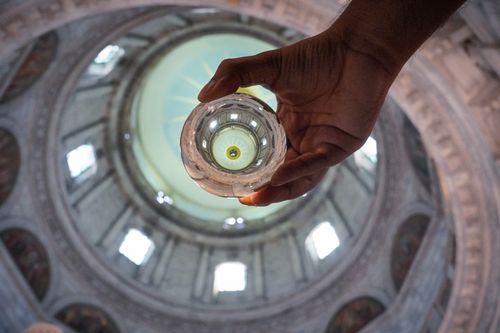 Free A hand holds a crystal ball reflecting an ornate dome, creating a unique perspective. Stock Photo