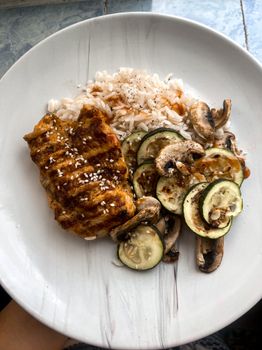 Delicious grilled chicken served with rice, zucchini, and mushrooms.