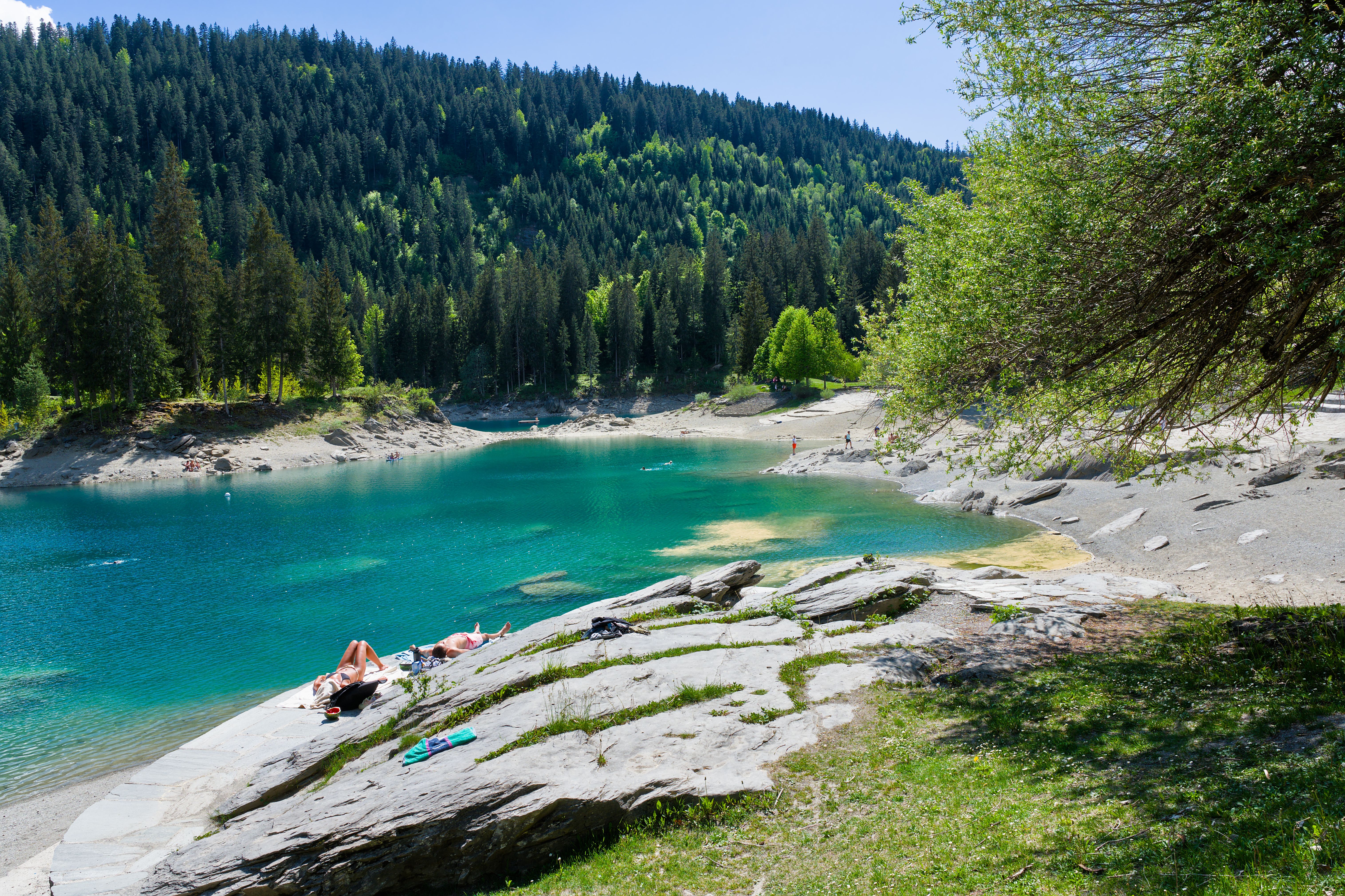 Relaxing summer afternoon by the turquoise Lake Cauma, surrounded by lush forests.