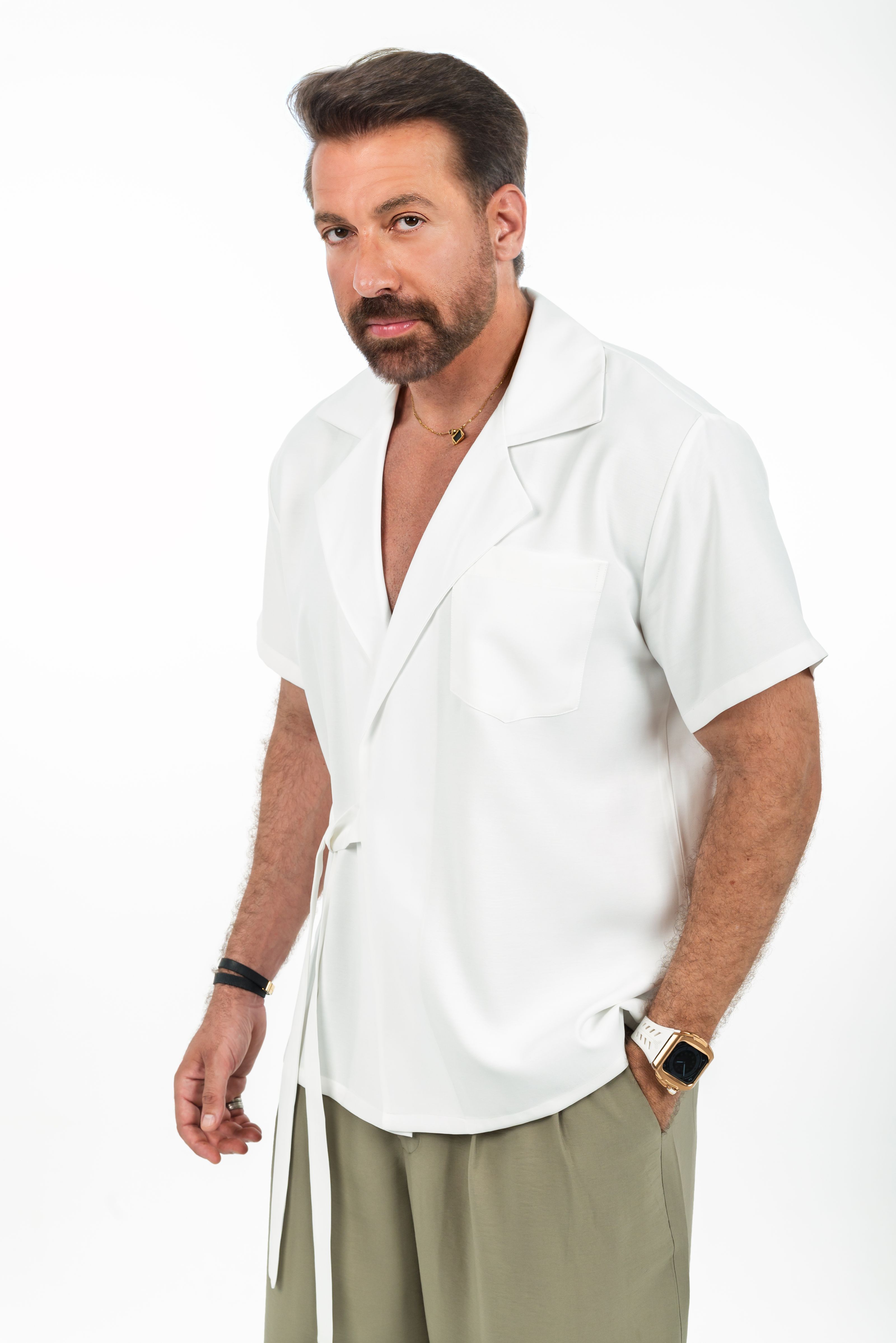 Homem estiloso vestindo camisa branca e calça casual, com um ar confiante.