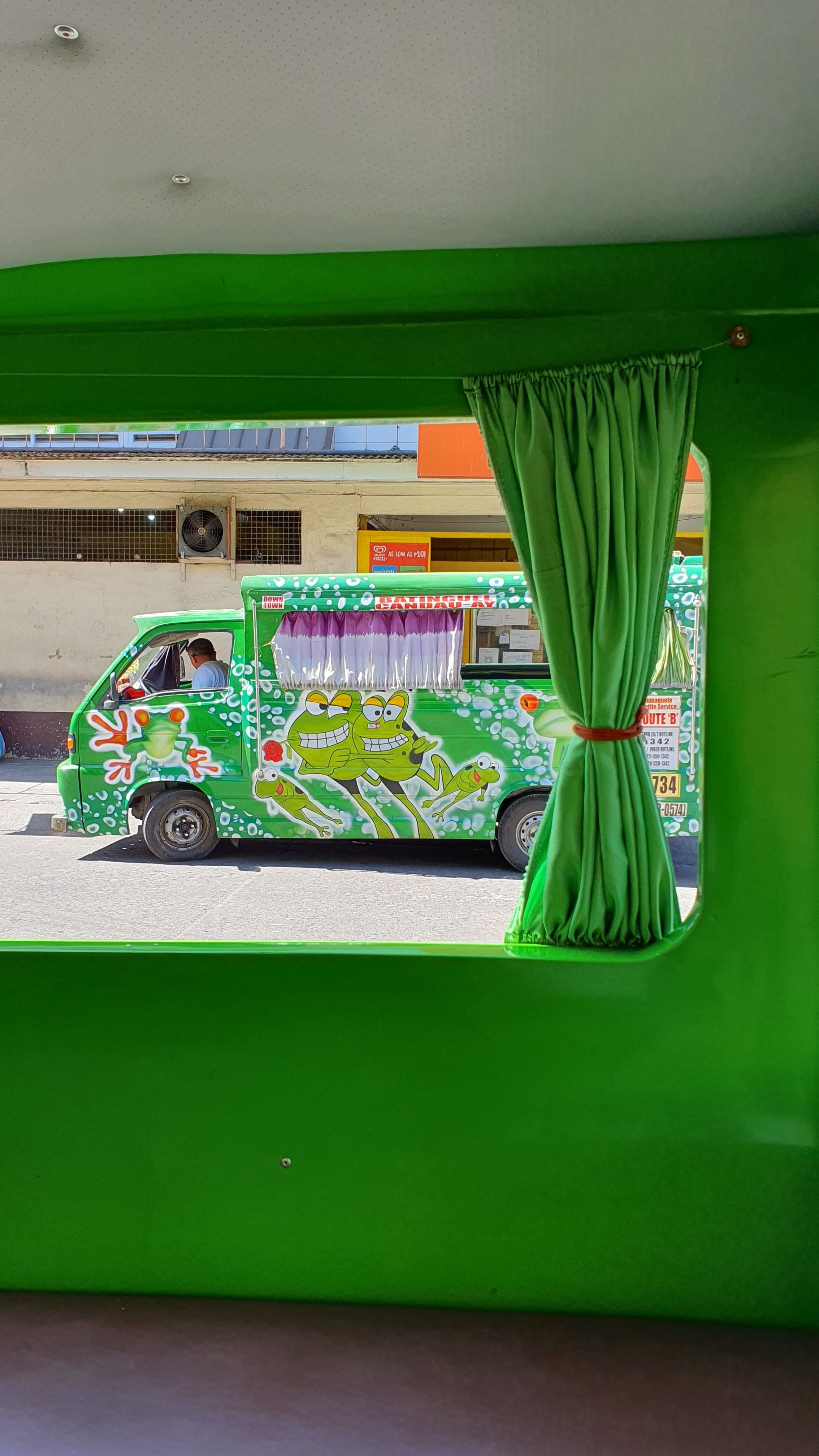 Colorful Street View Through Green Window with Minivan · Free Stock Photo