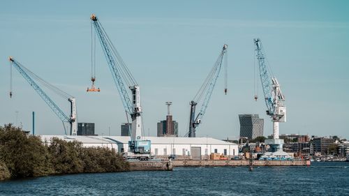 Free View of cranes and buildings along the Hamburg harbor under a clear sky. Stock Photo