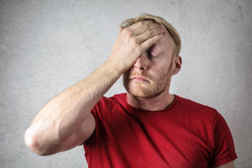 A Man in Red Shirt Covering His Face 