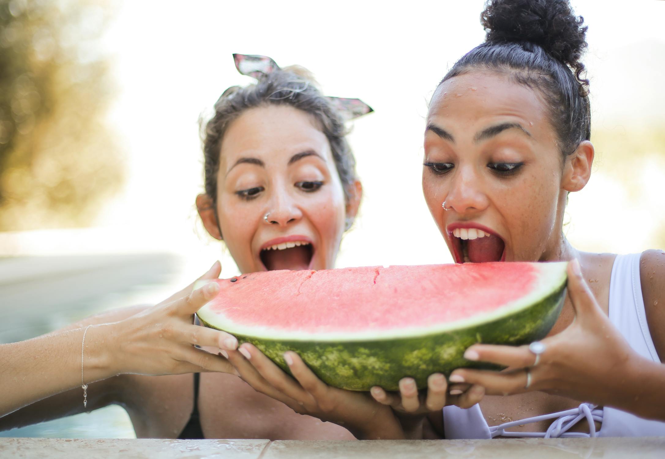 2 women taking a bite out of watermelon slice