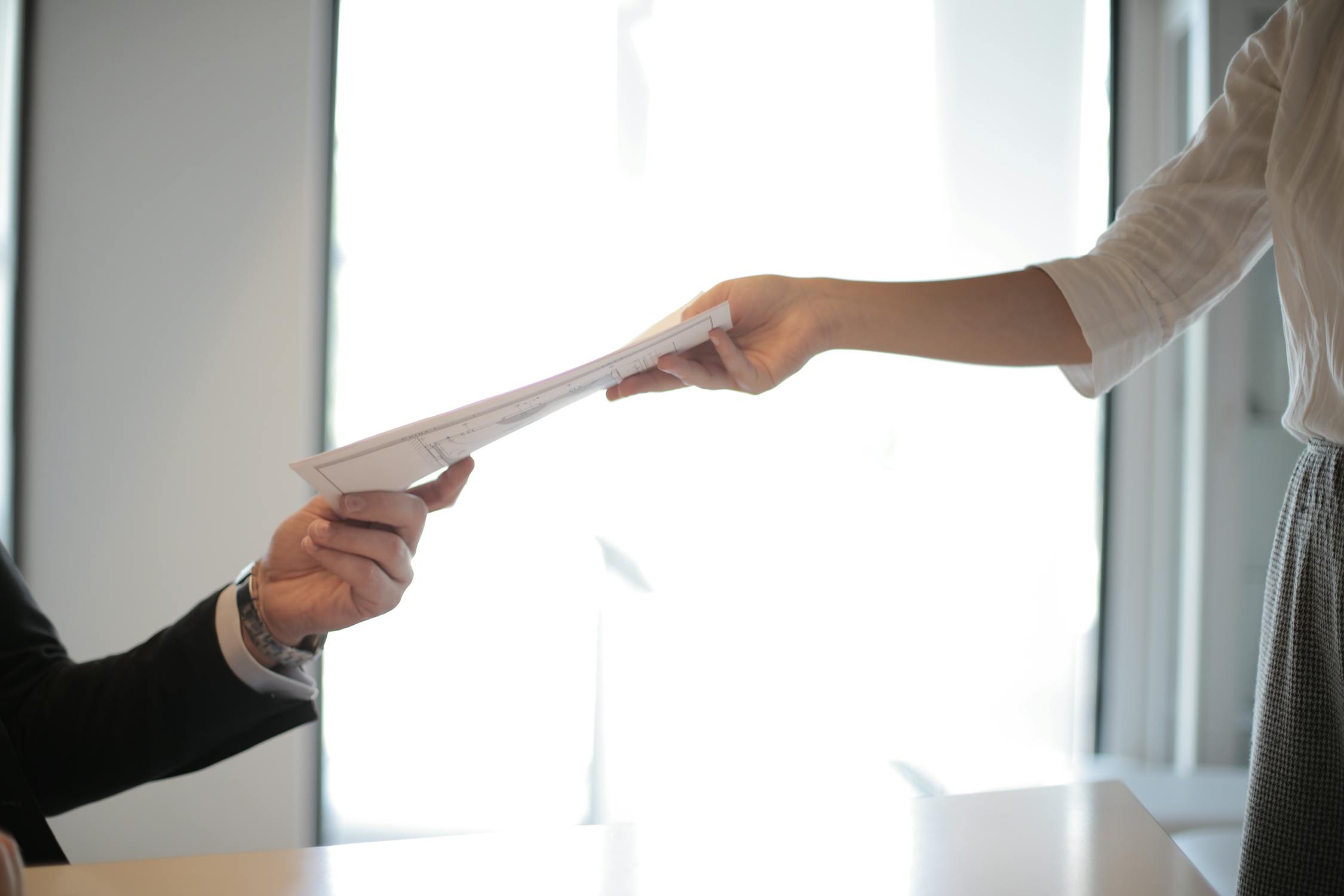 A close up of one person handing an application to another person