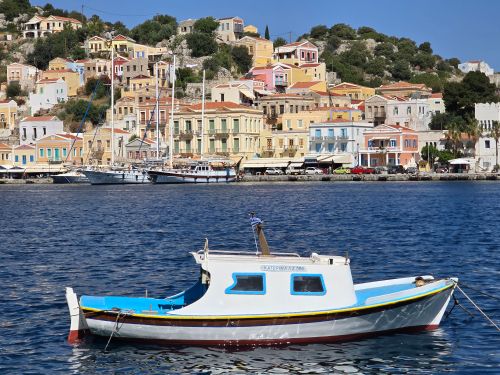 Free Traditional boat in Symi, Greece with vibrant hillside homes. Stock Photo