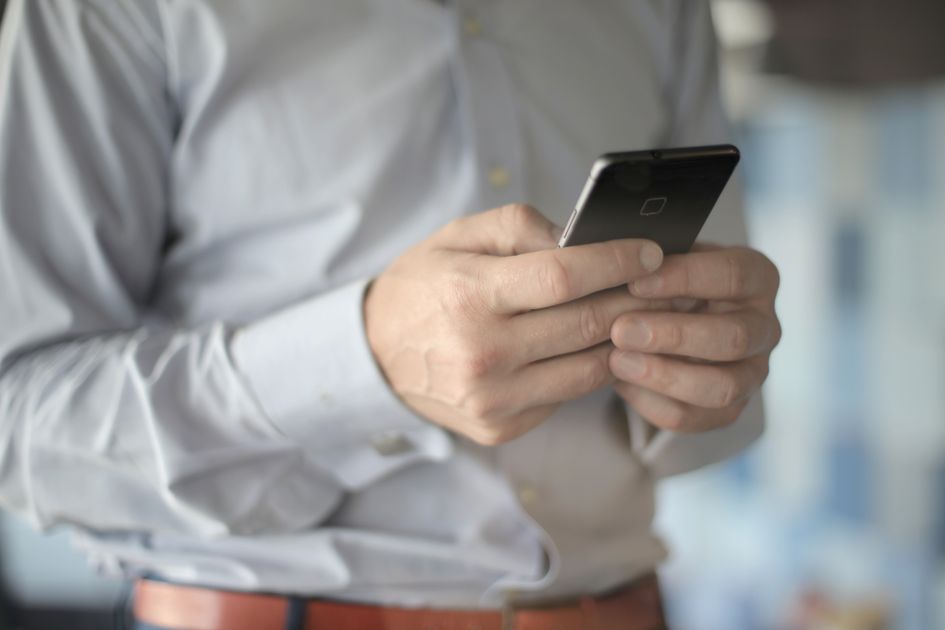 Un homme en costume consulte son smartphone dans la rue, entre deux rendez-vous.