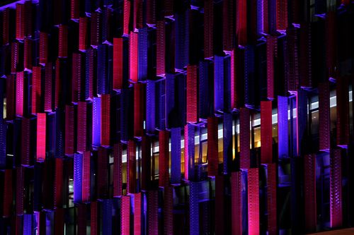 Free Stunning modern building facade in Tirana illuminated with vivid purple and red night lights. Stock Photo