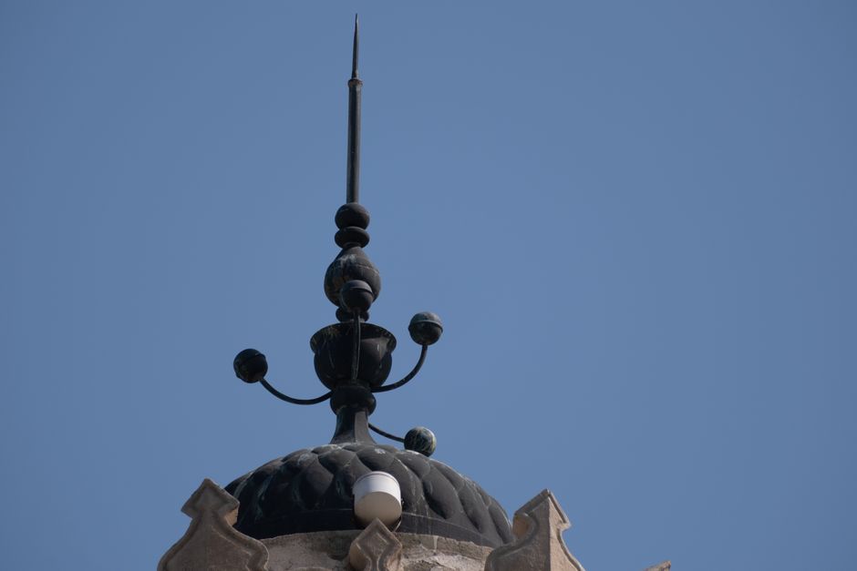 Vista detallada de una aguja decorativa en un edificio histórico en Izmir, Turquía, con un cielo azul despejado de fondo.