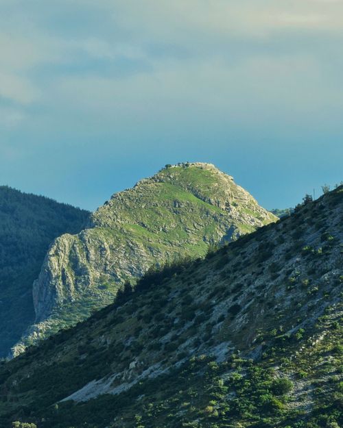 Free Captivating view of a mountain peak surrounded by lush greenery under a vibrant sky. Stock Photo