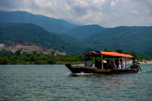 Free A traditional boat glides through picturesque waters in Sylhet, Bangladesh, amidst lush green mountains. Stock Photo