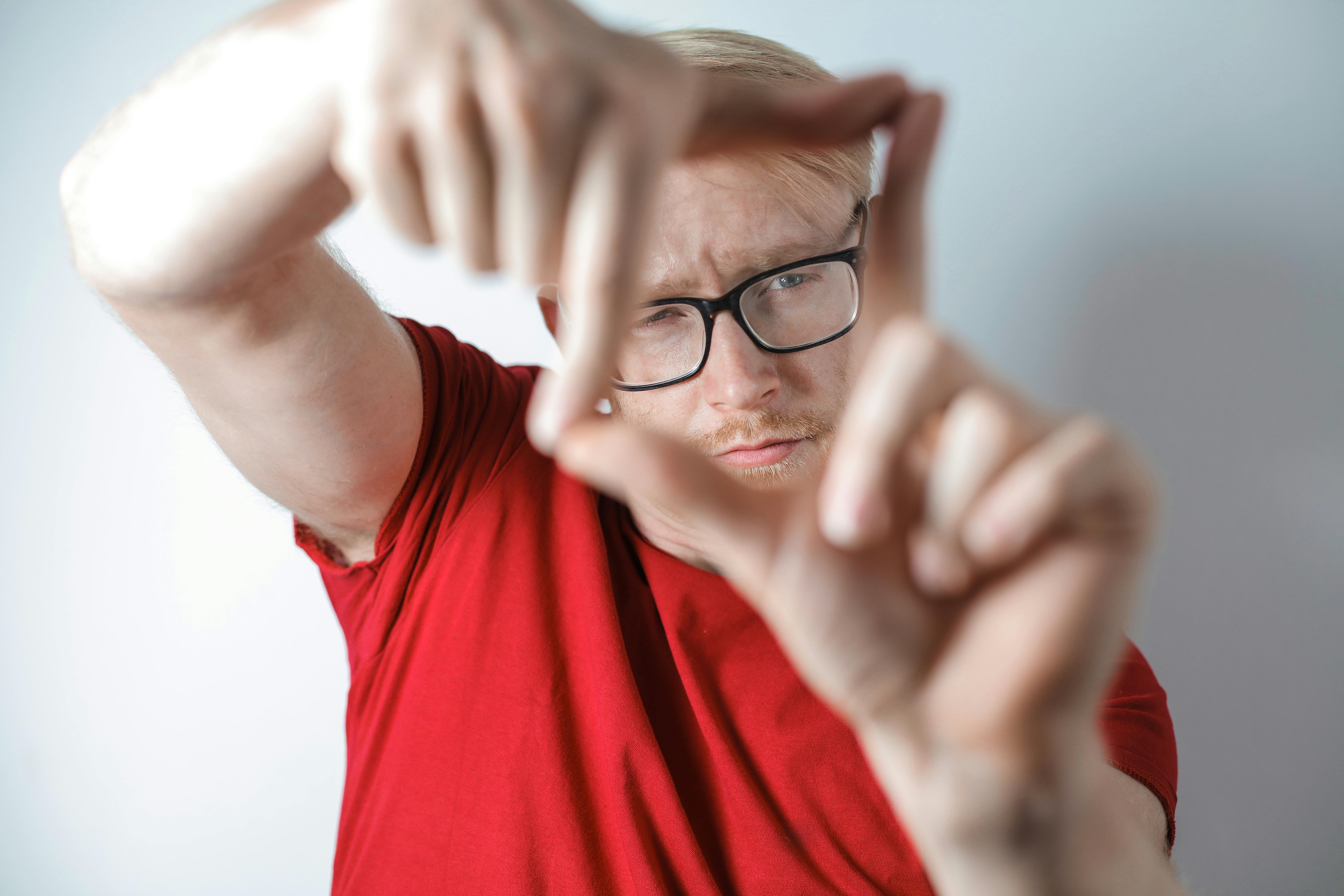 一个戴眼镜的男人用手框住脸，展现创造力