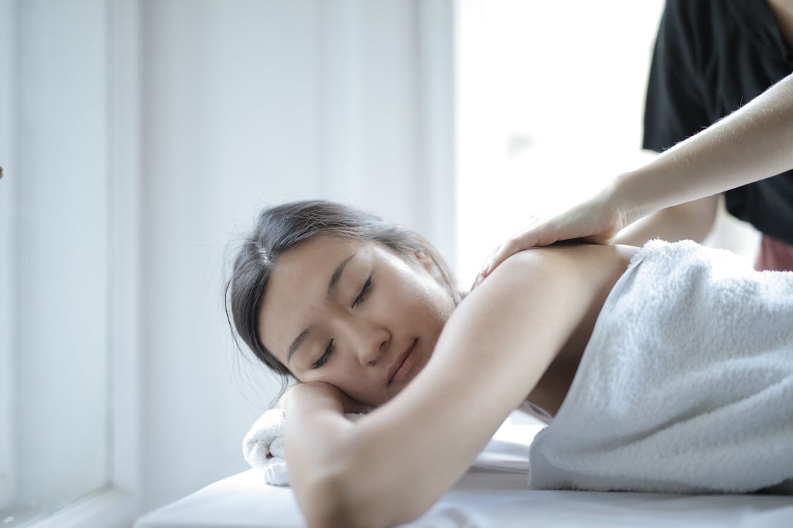 Woman with muscles tense taking a deep breath getting a massage as a stress response
