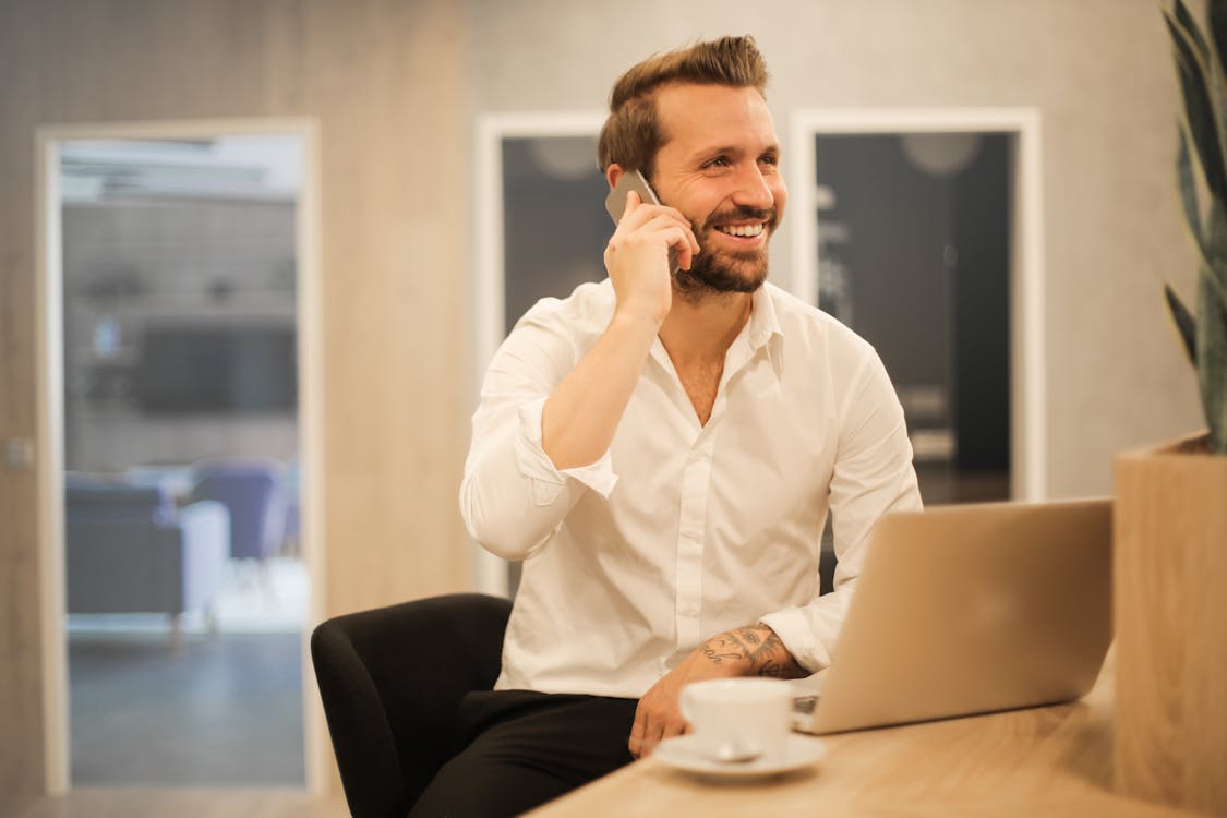 Sorridente Maschio Formale Con Laptop In Chat Tramite Telefono