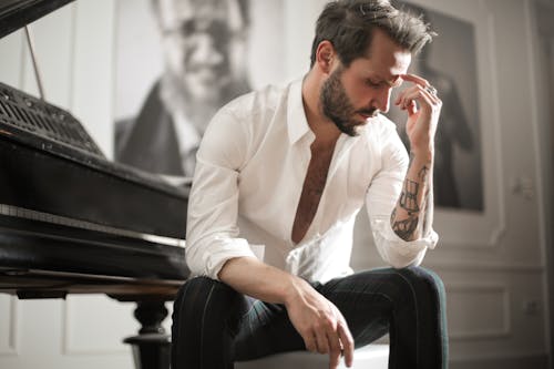 피아노에 앉아 극적인 문신 된 남성