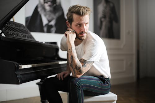 Man in White Shirt Sitting Beside  Piano