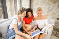 三个年轻女人在室内舒适的沙发上一起看书，享受闲暇时光