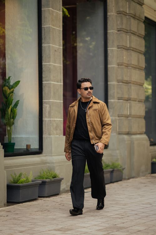 Free Stylish man in sunglasses walks past urban storefronts, exuding confidence and modern fashion Stock Photo
