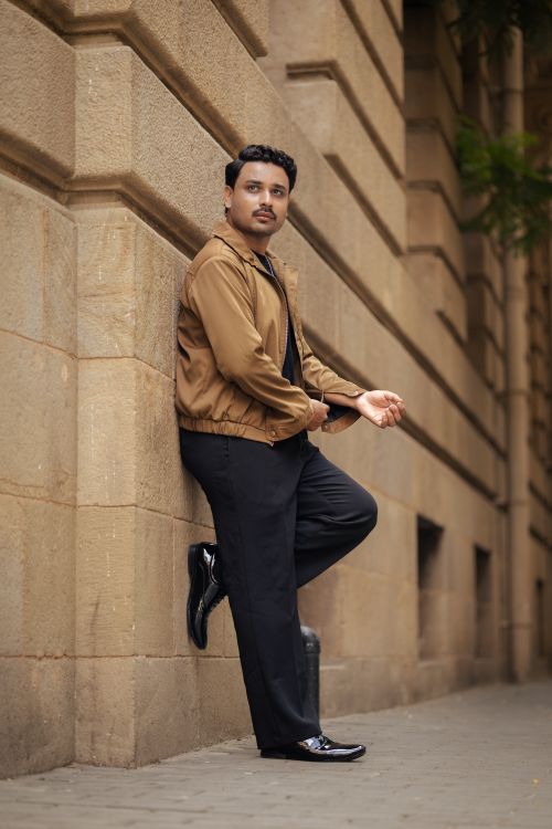 Free Confident man in casual chic attire poses against a historic urban building wall. Stock Photo