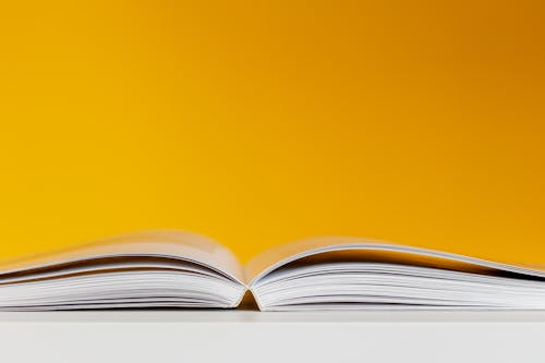 Gratis lagerfoto af åben bog, gul baggrund, konceptuel