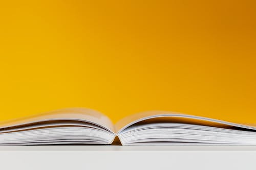 White Book In White Table Near Yellow Wall