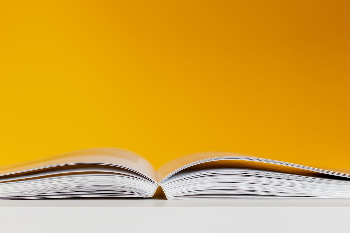 Free Opened Book on a Yellow Background  Stock Photo