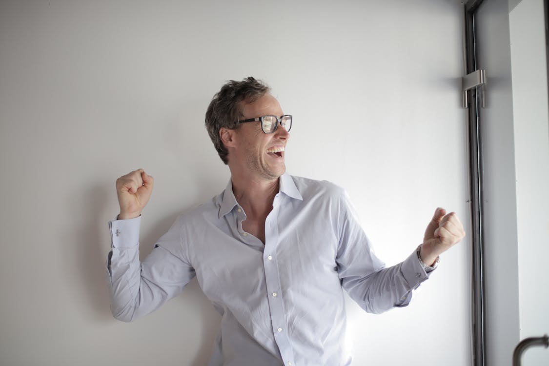 Free Portrait Photo of Laughing Man in White Dress Shirt and Black Framed Eyeglasses Celebrating Stock Photo