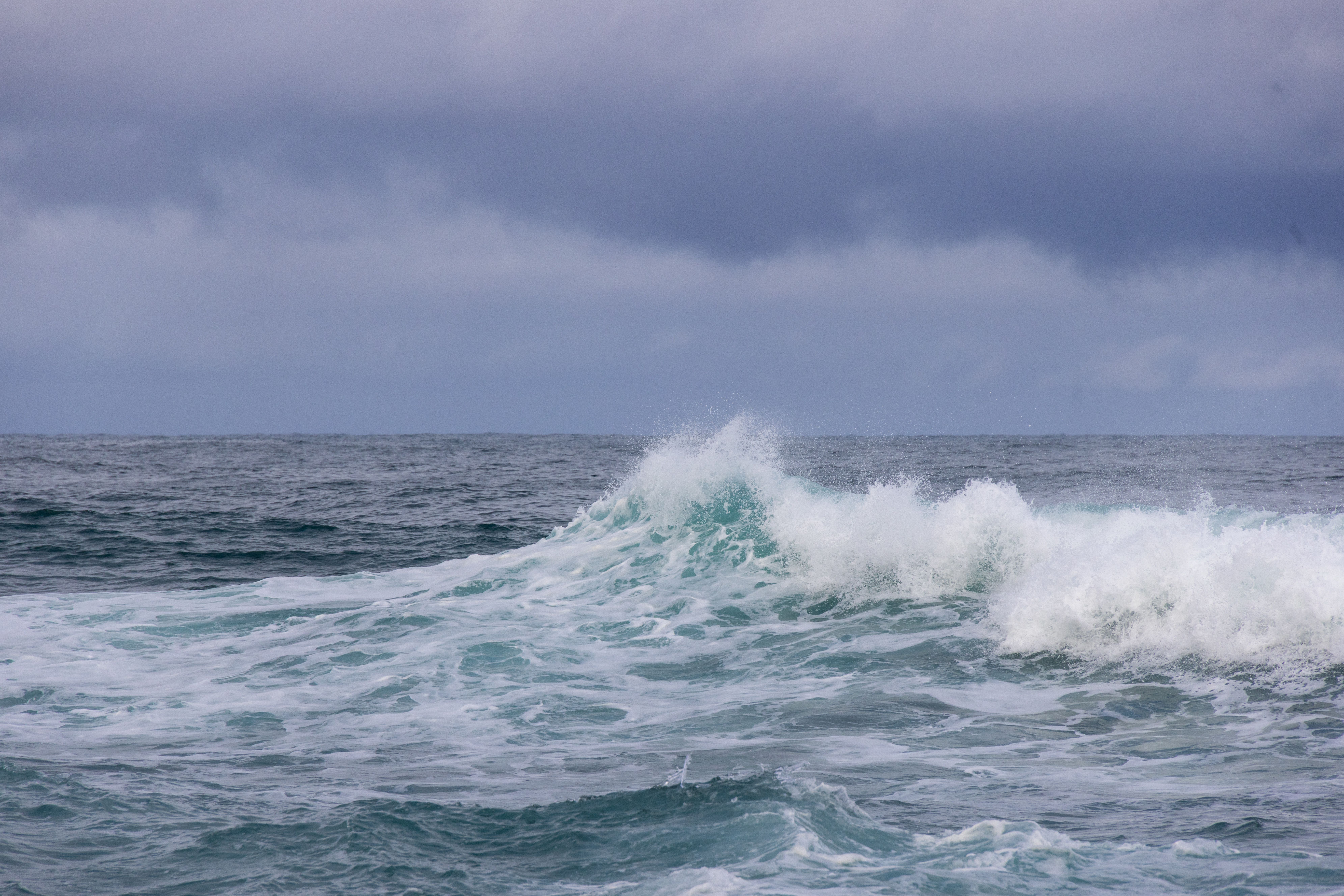 POV shot of a hand pointing towards endless ocean from a kayak, symbolizing adventure and exploration.