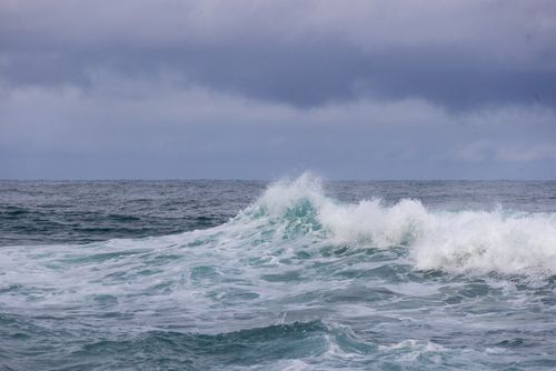 Free Powerful ocean waves crashing under a cloudy sky, showcasing nature's raw beauty. Stock Photo