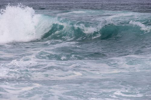 Free Dynamic ocean waves crash against each other with foamy whitecaps under a cloudy sky. Stock Photo