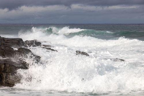 Free Powerful ocean waves crashing against rocky shoreline under cloudy sky, showcasing nature's raw beauty. Stock Photo