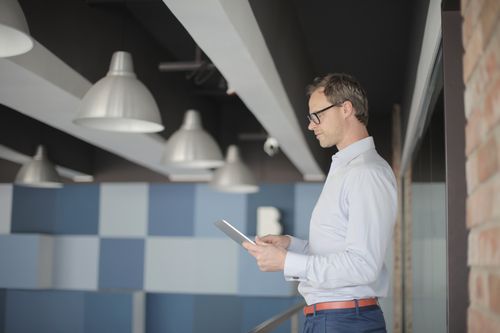 Free Businessman in smart casual using a tablet in a modern office setting. Stock Photo