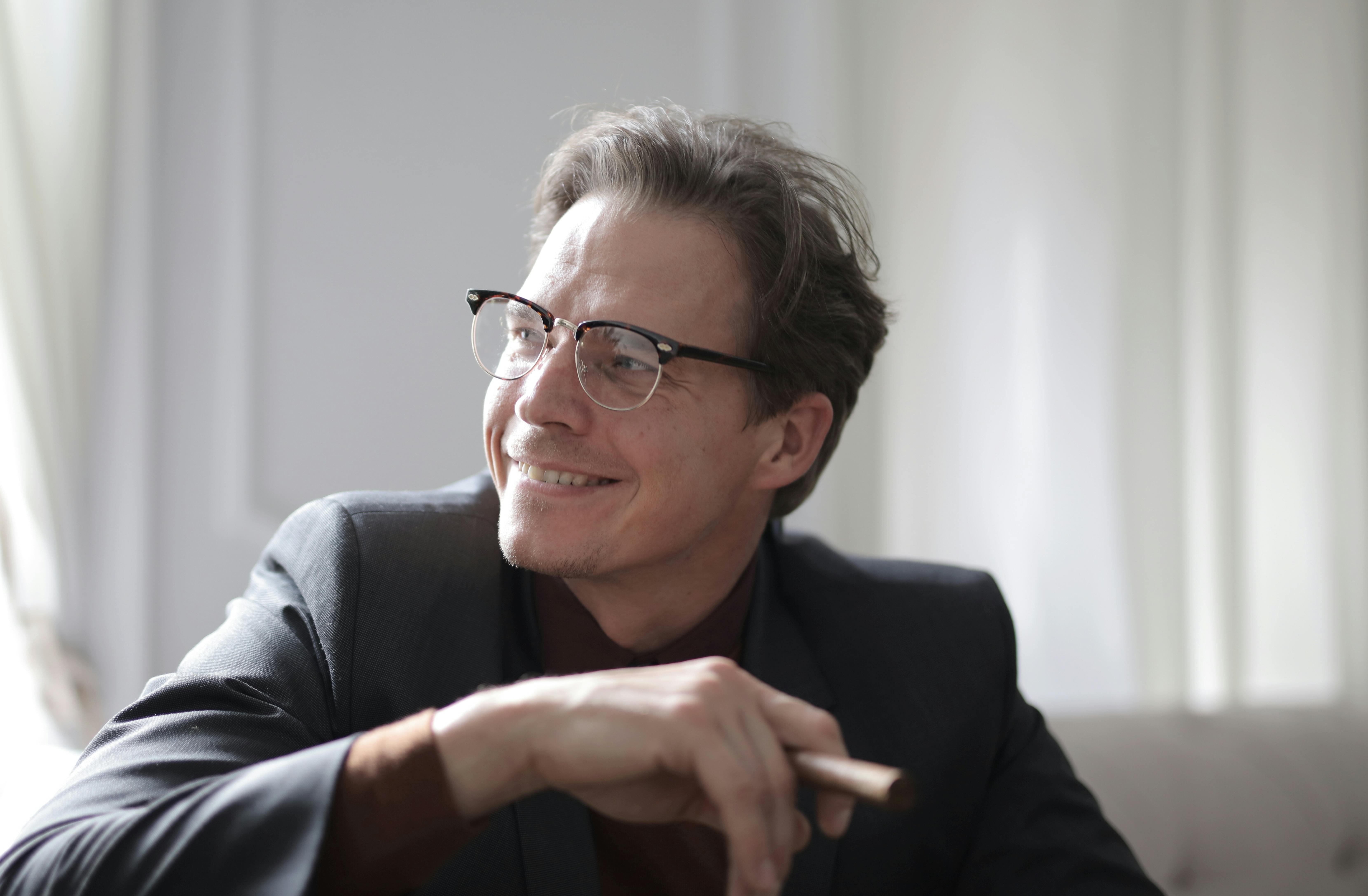 一位戴着眼镜、面带微笑的商人手持雪茄，散发着自信与温暖