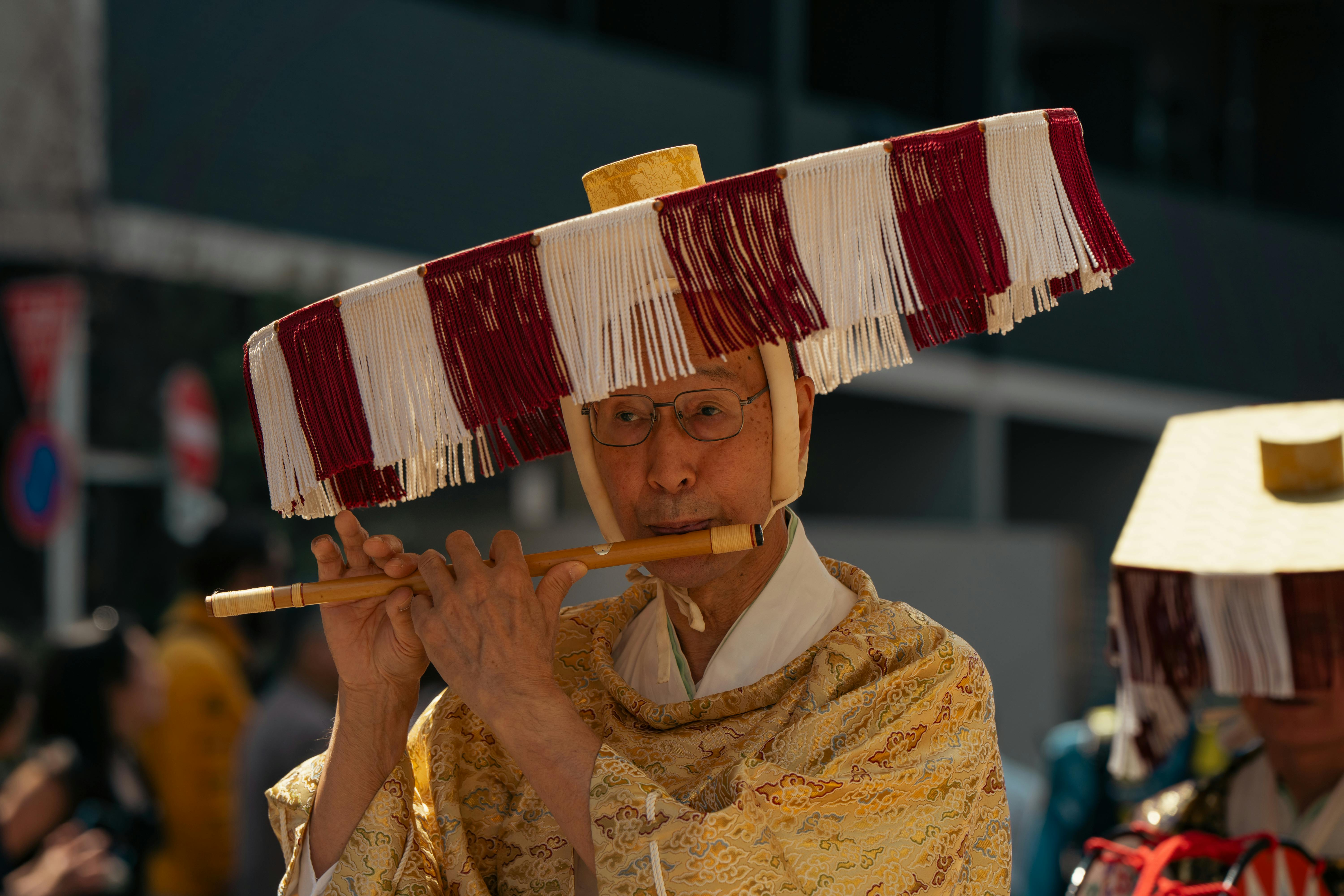 A musician in traditional attire plays a flute during a festive street parade in Tokyo, Japan.