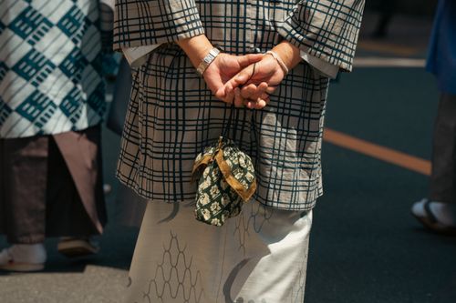 Free Person in traditional Japanese kimono standing on a Tokyo street, hands clasped behind back. Stock Photo